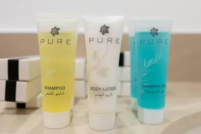a group of three bottles of sunscreen on a counter at Nice 1Bedroom - UNA Townsquare in Dubai