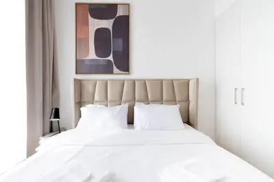 a white bed with white sheets and pillows at Nice 1Bedroom - UNA Townsquare in Dubai