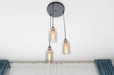 aendant light with bulbs and a clock on a ceiling at Nice 1Bedroom - UNA Townsquare in Dubai