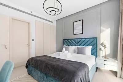 a bedroom with a large bed with a blue headboard at Silkhaus chic 1BDR in west avenue with Pool & gym access in Dubai