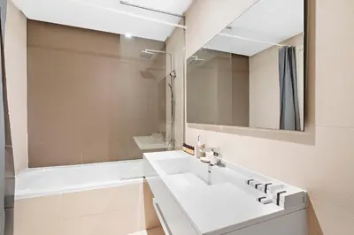 a white bathroom with a sink and a mirror at Silkhaus chic 1BDR in west avenue with Pool & gym access in Dubai