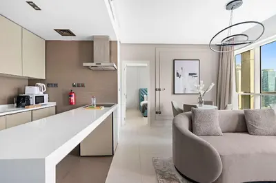 a kitchen and living room with a couch and a table at Silkhaus chic 1BDR in west avenue with Pool & gym access in Dubai