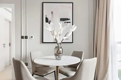 a dining room with a table with chairs and a vase with flowers at Silkhaus chic 1BDR in west avenue with Pool & gym access in Dubai