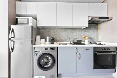 a kitchen with a washing machine and a refrigerator at Silkhaus spacious studio in Art Gardens with gym & pool access in Dubai