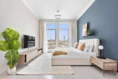 a bedroom with a bed and a large window at Silkhaus beautiful studio in Art Gardens with pool access in Dubai