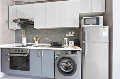a kitchen with a washing machine and a refrigerator at Silkhaus beautiful studio in Art Gardens with pool access in Dubai