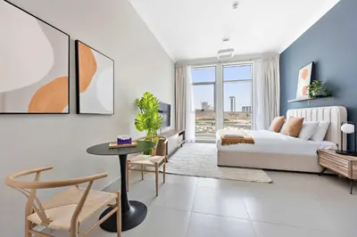 a bedroom with a bed and a table and chairs at Silkhaus beautiful studio in Art Gardens with pool access in Dubai