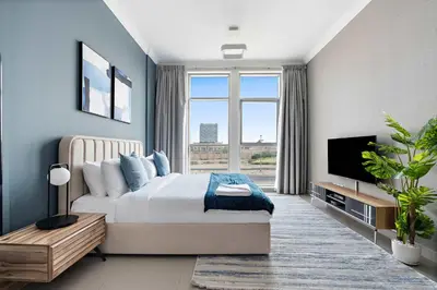 a bedroom with a bed and a flat screen tv at Silkhaus new studio in Art Gardens pool access in Dubai