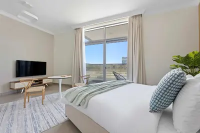 a bedroom with a bed and a large window at Silkhaus new studio in Art Gardens gym & pool access in Dubai
