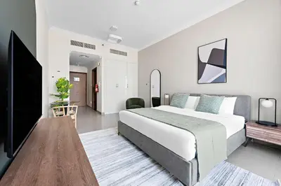 a bedroom with a large bed and a flat screen tv at Silkhaus Chic Studio in Art Gardens Modern Living in Dubai