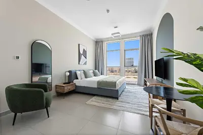 a bedroom with a bed and a table and a tv at Silkhaus Chic Studio in Art Gardens Modern Living in Dubai