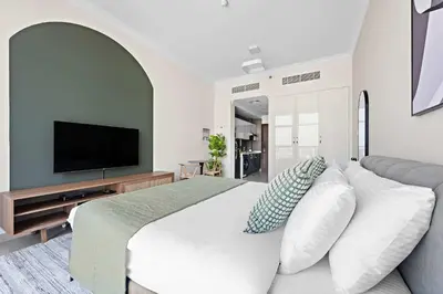a bedroom with a large bed with a television at Silkhaus Chic Studio in Art Gardens Modern Living in Dubai