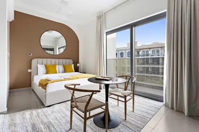 a bedroom with a bed and a table and a window at Silkhaus aesthetic studio in Art Gardens with gym & pool access in Dubai