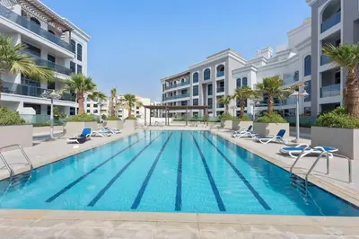 a swimming pool with lounge chairs and a building at Silkhaus aesthetic studio in Art Gardens with gym & pool access in Dubai