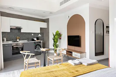 a kitchen and living room with a table and chairs at Silkhaus aesthetic studio in Art Gardens with gym & pool access in Dubai