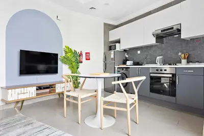 a kitchen with a table and chairs and a tv at Silkhaus luxurious studio in Art Gardens with gym access in Dubai