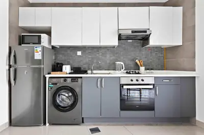 a kitchen with white cabinets and a washing machine at Silkhaus luxurious studio in Art Gardens with gym access in Dubai