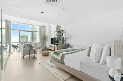 a white bedroom with a large bed and a living room at Silkhaus modern studio in Liberty House in Dubai