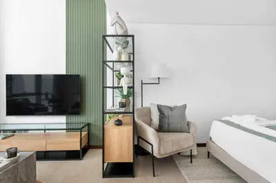 a bedroom with a bed and a chair and a tv at Silkhaus modern studio in Liberty House in Dubai