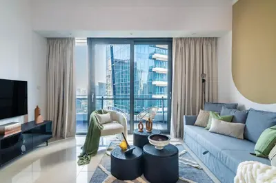 a living room with a blue couch and a large window at The Smart Concierge - Silverene in Dubai