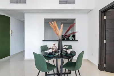 a dining room with a black table and green chairs at The Smart Concierge - Silverene in Dubai