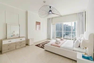 a white bedroom with a large bed and a window at RH- Urban Living, spacious 01BR, near burj Khalifa in Dubai