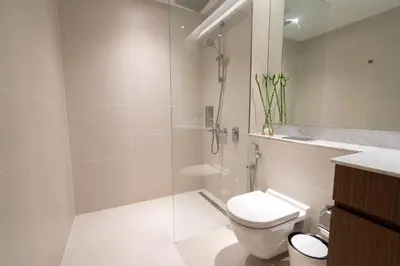 a bathroom with a toilet and a glass shower at HiGuests - Stylish Waterfront Retreat With Balcony in La Mer in Dubai