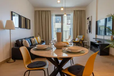a living room with a table with chairs and a couch at HiGuests - Stylish Waterfront Retreat With Balcony in La Mer in Dubai