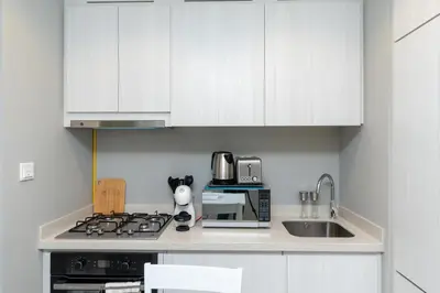 a kitchen with white cabinets and a stove and a sink at White Sage - DAMAC Zada Tower in Dubai