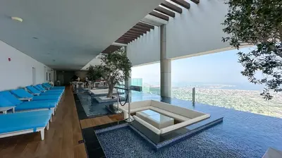 an open living room with blue chairs and a pool at Stunning 2BR with Burj Views Infinity Pool in Dubai