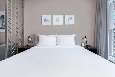 a bedroom with a large white bed and two lamps at White Sage - Fancy Studio With Mesmerizing Canal Views in Dubai