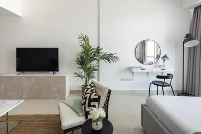 a white living room with a tv and a couch at Frank Porter - Oasis Tower 1 in Dubai