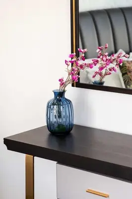 a blue vase with flowers on a table in front of a mirror at Frank Porter - Bayz Tower by Danube in Dubai