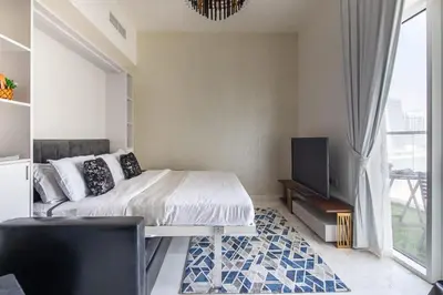 a bedroom with a bed and a flat screen tv at Frank Porter - Bayz Tower by Danube in Dubai