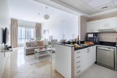 a kitchen with white cabinets and a living room at Frank Porter - Concorde Tower in Dubai