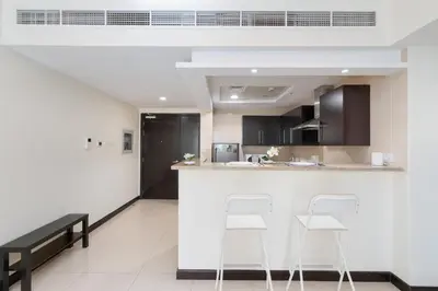 a kitchen with two white stools and a counter at White Sage - Gorgeous Apartment in JLT Near the Metro Station in Dubai