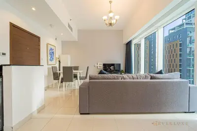 a living room with a couch and a large window at Everluxe Lovely Studio Apt In Business Bay in Dubai