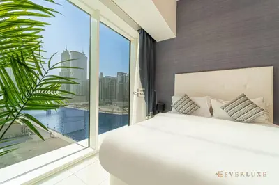 a bedroom with a white bed and a large window at Everluxe Lovely Studio Apt In Business Bay in Dubai