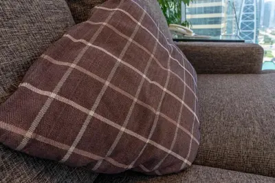 a brown and white plaid pillow on a couch at Summer Deal! Stylish 1 BR in Jumeirah Lake Towers in Dubai