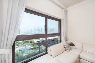 a white couch in a room with a large window at Daniels Sea View 2BR in Fairmont The Palm in Dubai