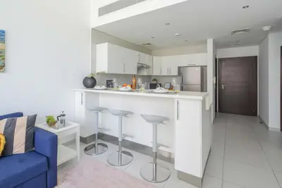 a kitchen and living room with a counter and a blue couch at Frank Porter - Panoramic Tower in Dubai