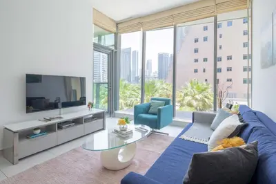 a living room with a blue couch and a large window at Frank Porter - Panoramic Tower in Dubai