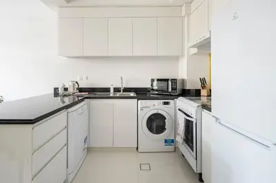 a white kitchen with a washer and dryer in it at Frank Porter - Tower 108 in Dubai