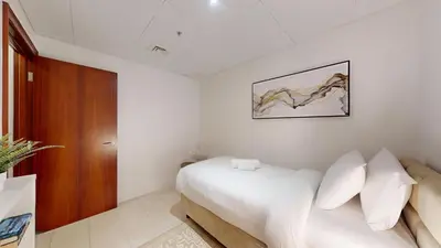 a bedroom with a white bed and a wooden door at Al Murjan - Appealing Two Bedroom in Dubai