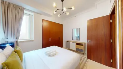 a bedroom with a white bed and a television at Al Murjan - Appealing Two Bedroom in Dubai
