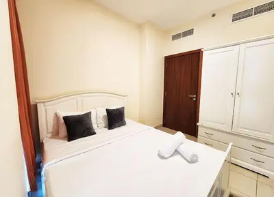 a bedroom with a white bed and a wooden cabinet at RH- The Perfect Family Getaway, 3BR in Standpoint Tower in Dubai