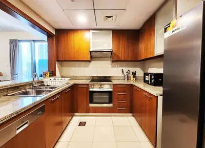 a kitchen with wooden cabinets and a stainless steel refrigerator at RH- The Perfect Family Getaway, 3BR in Standpoint Tower in Dubai