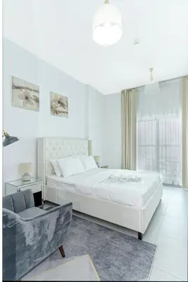 a white bedroom with a large bed and a couch at Modern Studio with Pool & Gym Access in Dubai