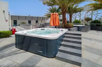a jacuzzi tub on a patio with palm trees at Modern Studio with Pool & Gym Access in Dubai