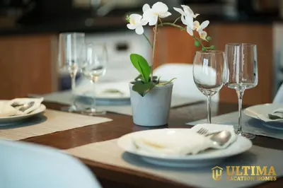a table with plates and glasses and a vase with flowers at Alluring 1BR Opp to JBR Beach- Marina Views in Dubai